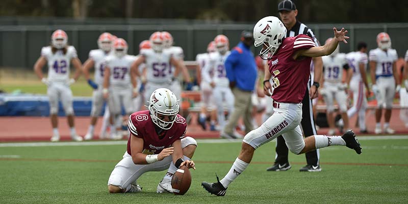 Camdin Dirnberger kicks the ball as Seth Beach holds.