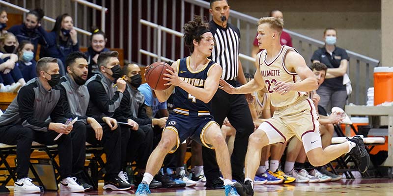 Jonathan Watts closed out to guard an offensive player with the Willamette coaching staff in the background.